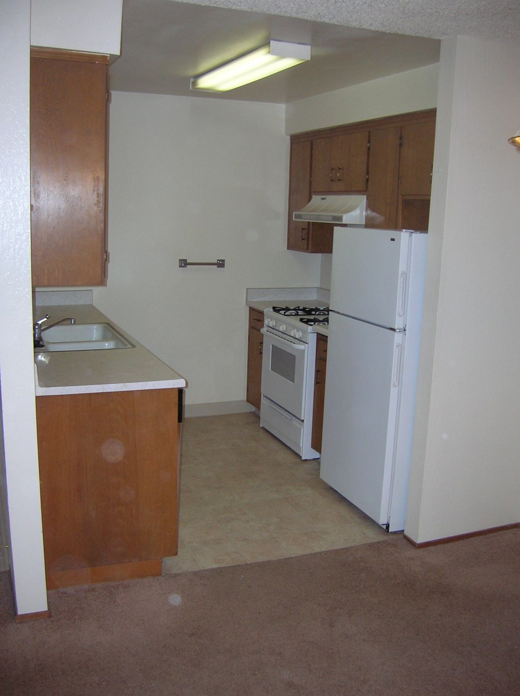 a kitchen with white appliances and wooden cabinets and a white refrigerator