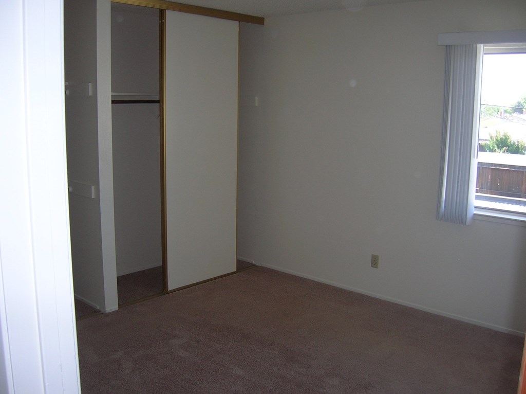an empty room with a closet and a window