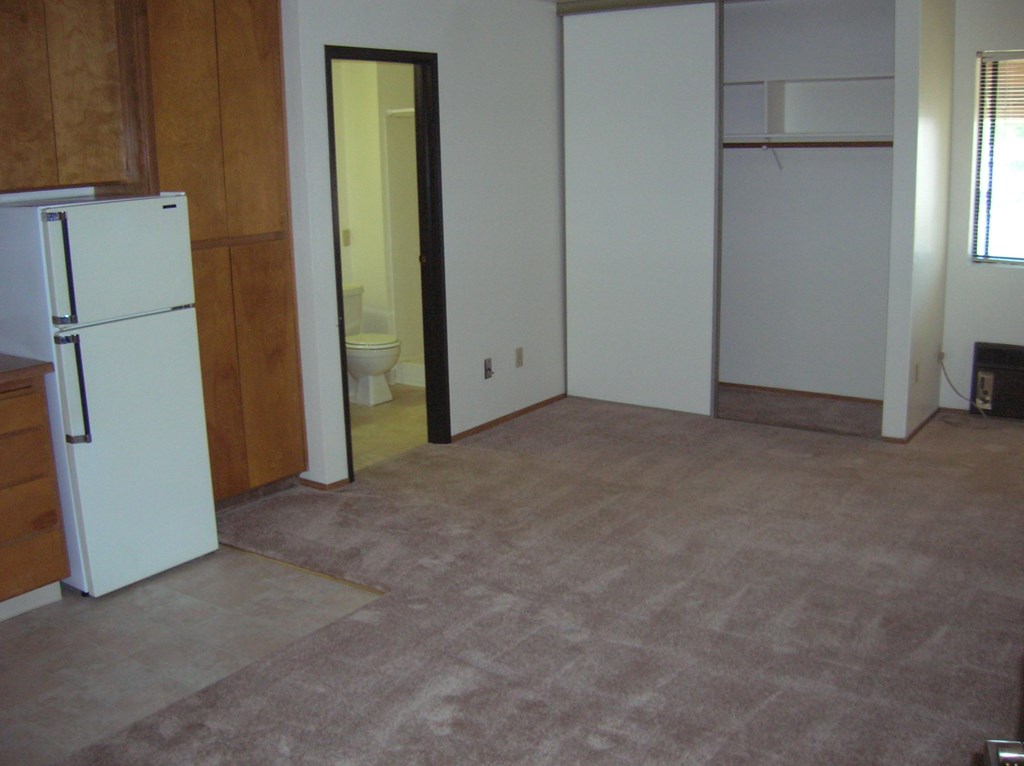 an empty room with a refrigerator and a door to a bathroom
