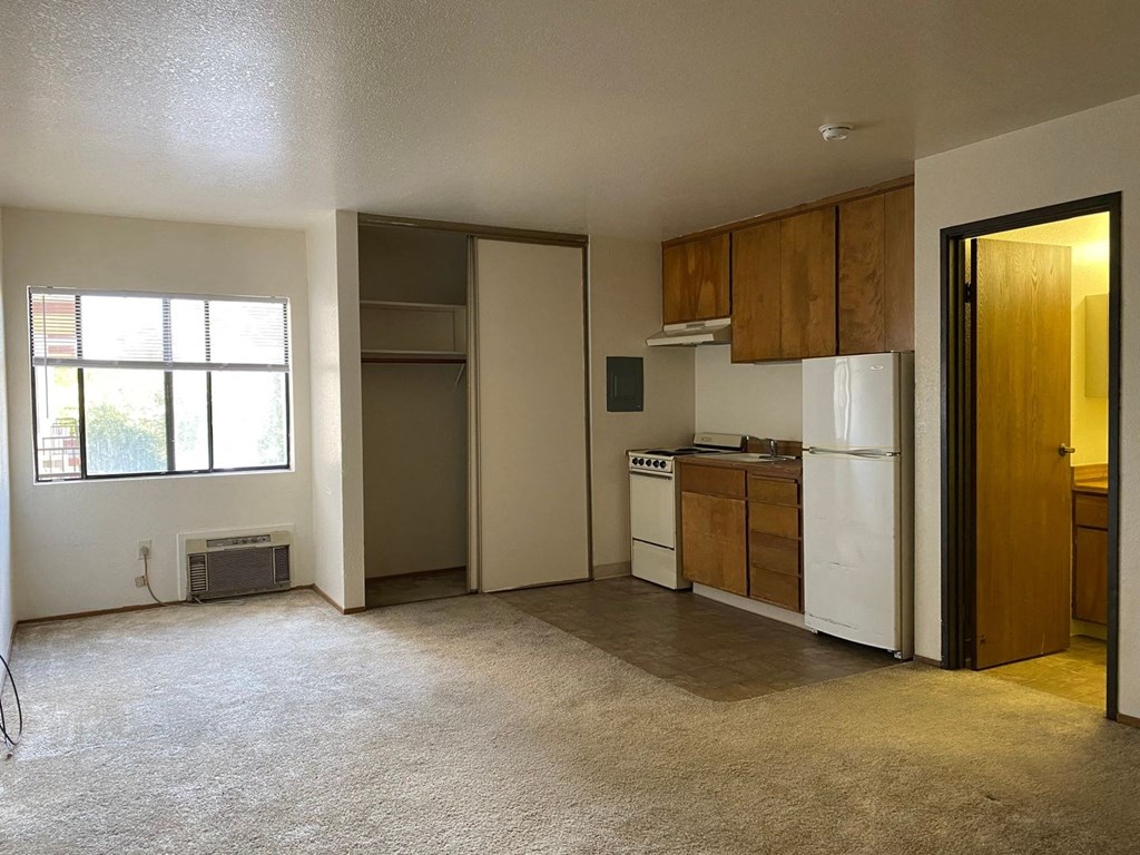 an empty kitchen with a white refrigerator and a window