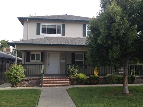the front of a house with a porch and a tree