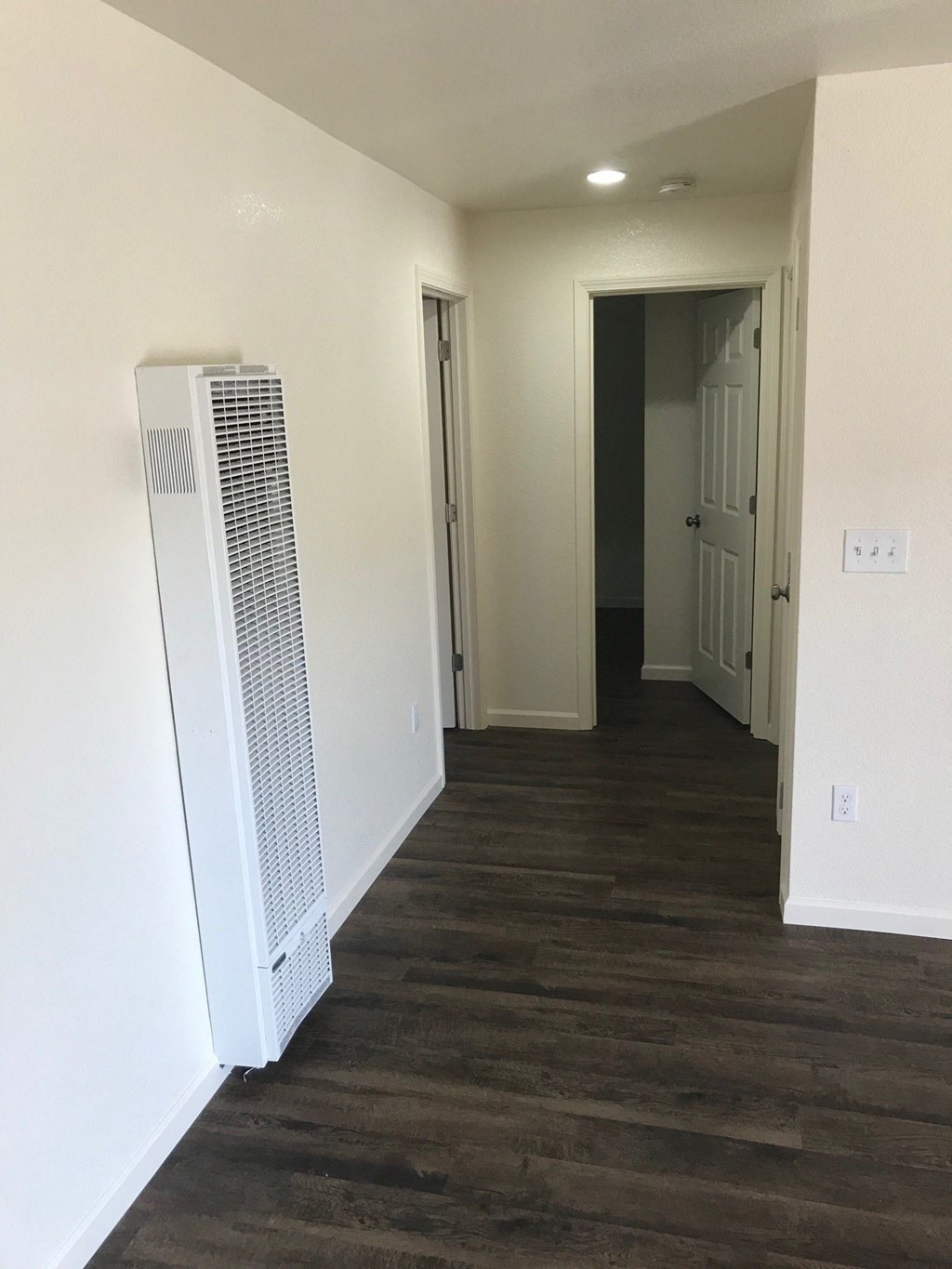 a living room with a heater and a hallway with a door to a closet