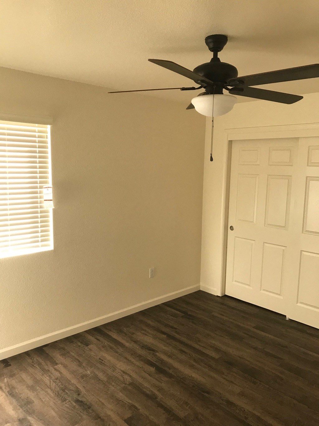 a living room with wood floors and a ceiling fan