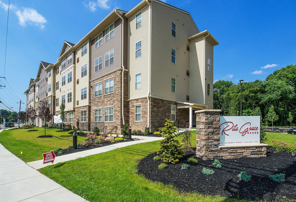 an apartment building with a sign in front of it on a sidewalk