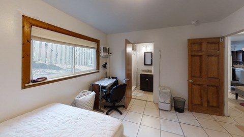 a bedroom with a bed and a desk and a window