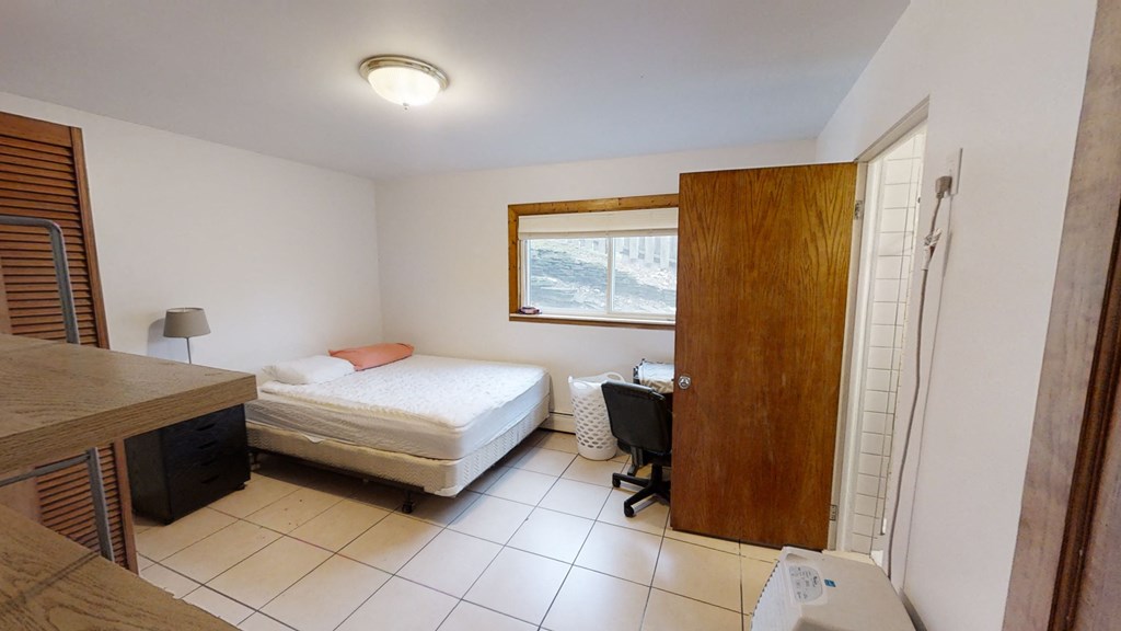 a bedroom with a bed and a desk and a window