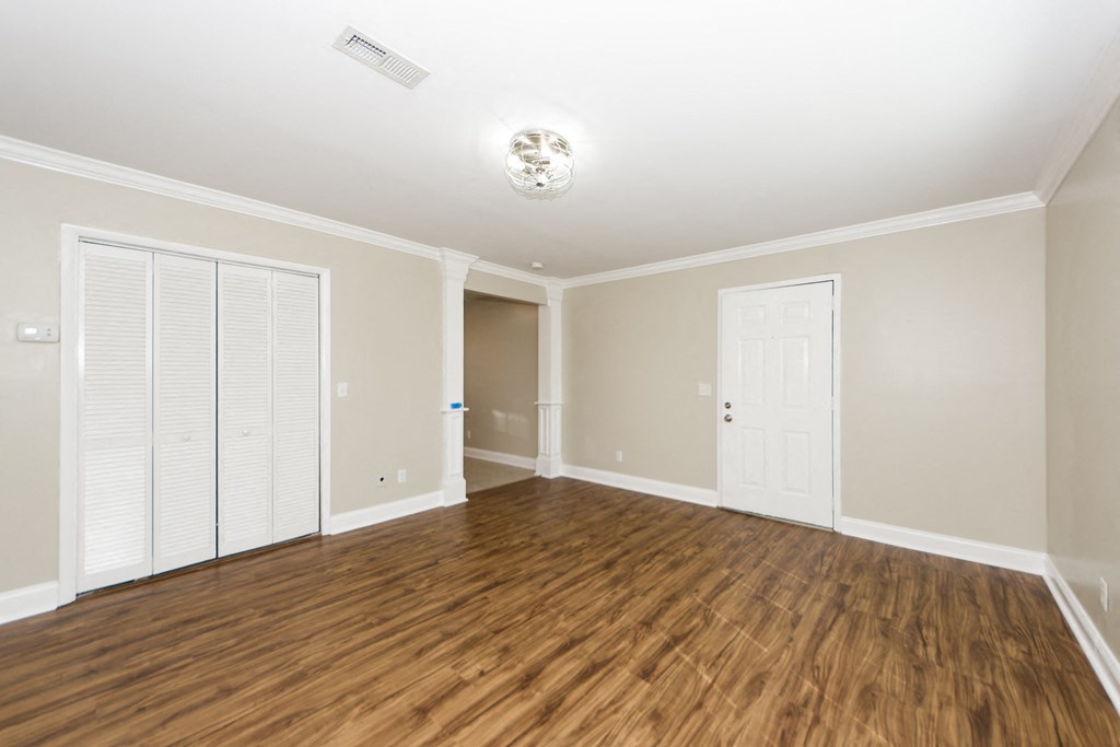 an empty living room with wood flooring and white walls