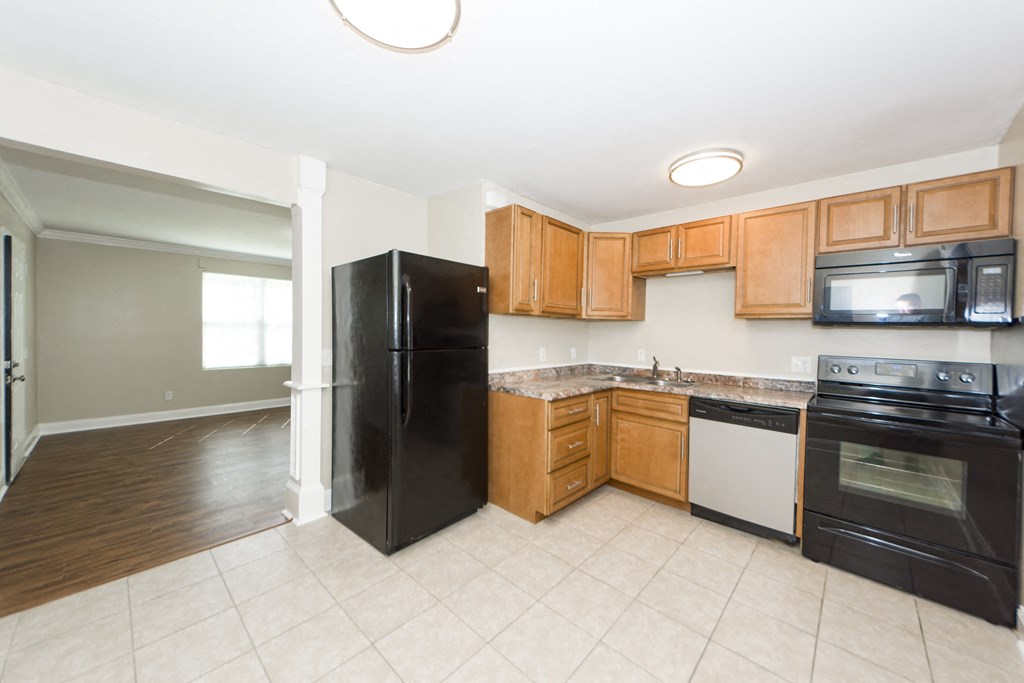 an empty kitchen with black appliances and wooden cabinets