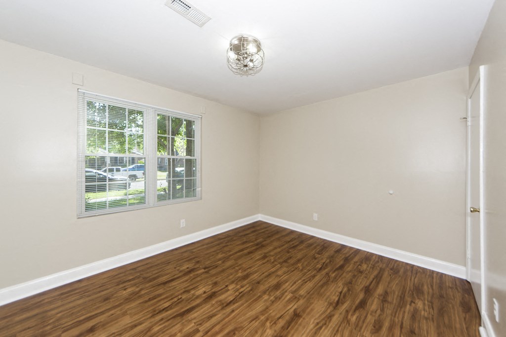 an empty living room with wood flooring and a window
