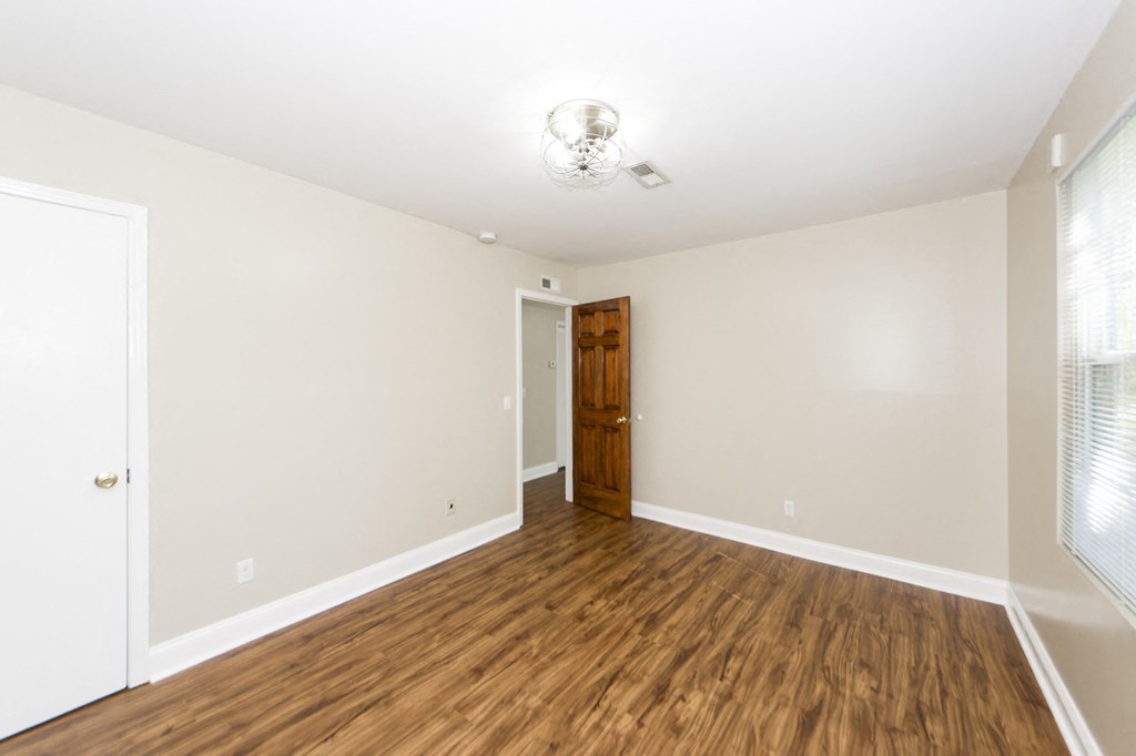 a living room with wood flooring and white walls and a door to a hallway