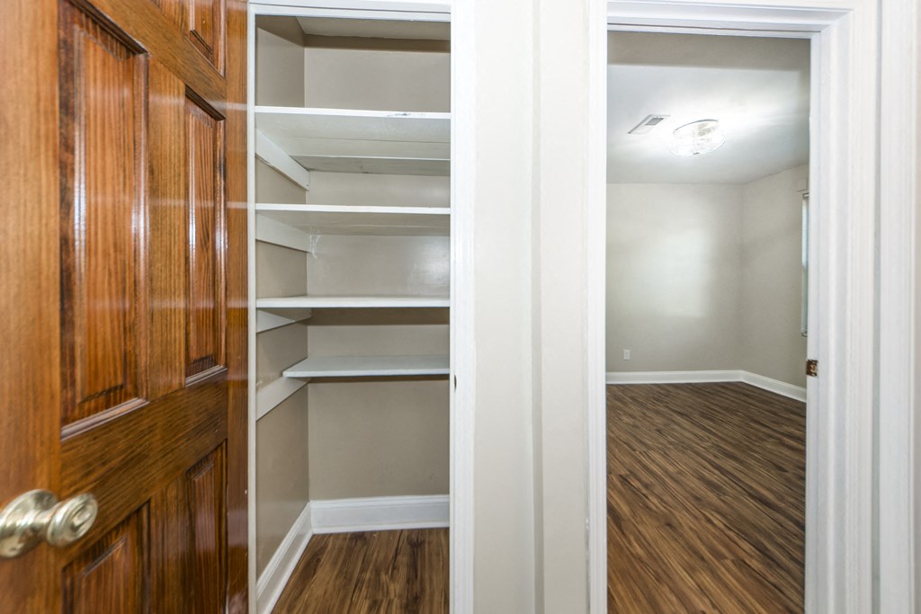 a walk in closet with shelves and a wooden closet door