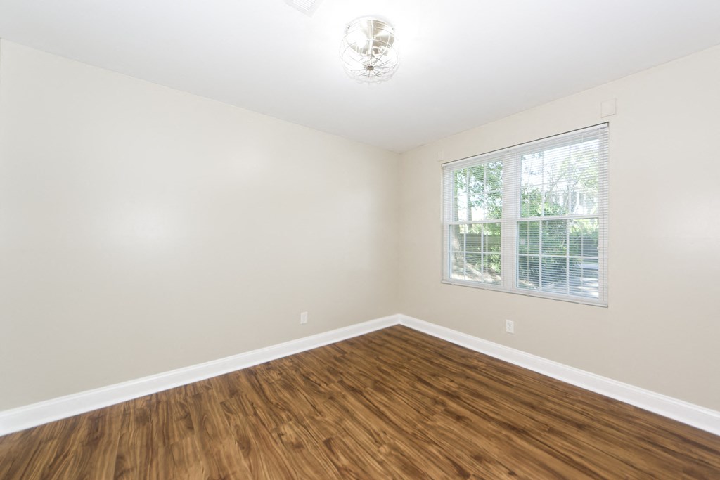 an empty living room with wood flooring and a window