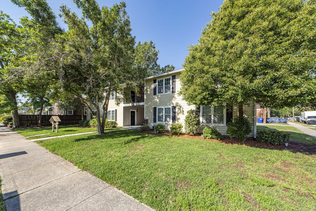 the front of a house with a lawn and trees