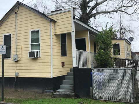 a yellow house with stairs and a fence