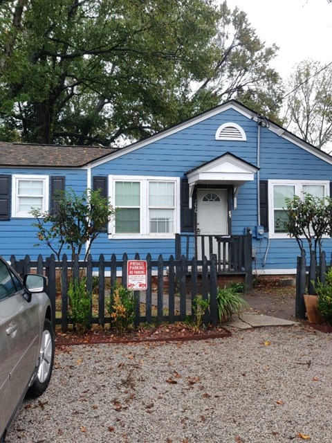 A blue house with a sign on the fence.