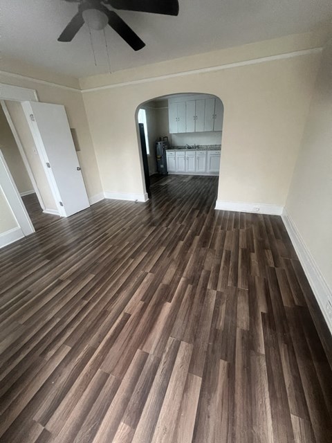 A room with a ceiling fan and wooden flooring.