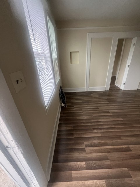 A hallway with wooden floors and white walls.