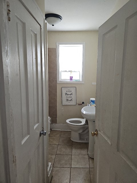 A bathroom with a toilet and a sign on the wall.