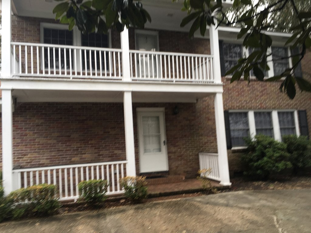 the front of a brick house with a white balcony