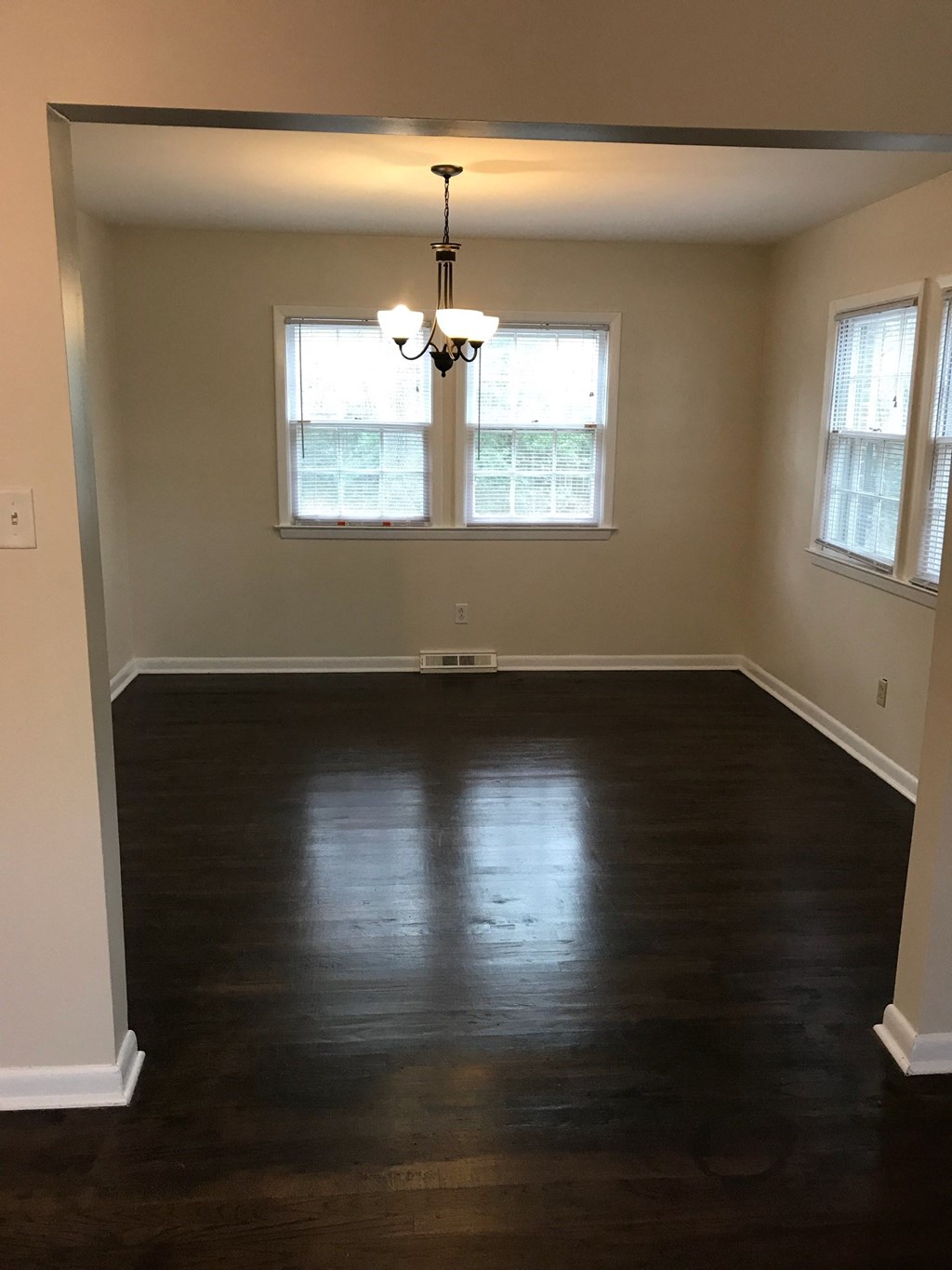 an empty living room with wood floors and a window