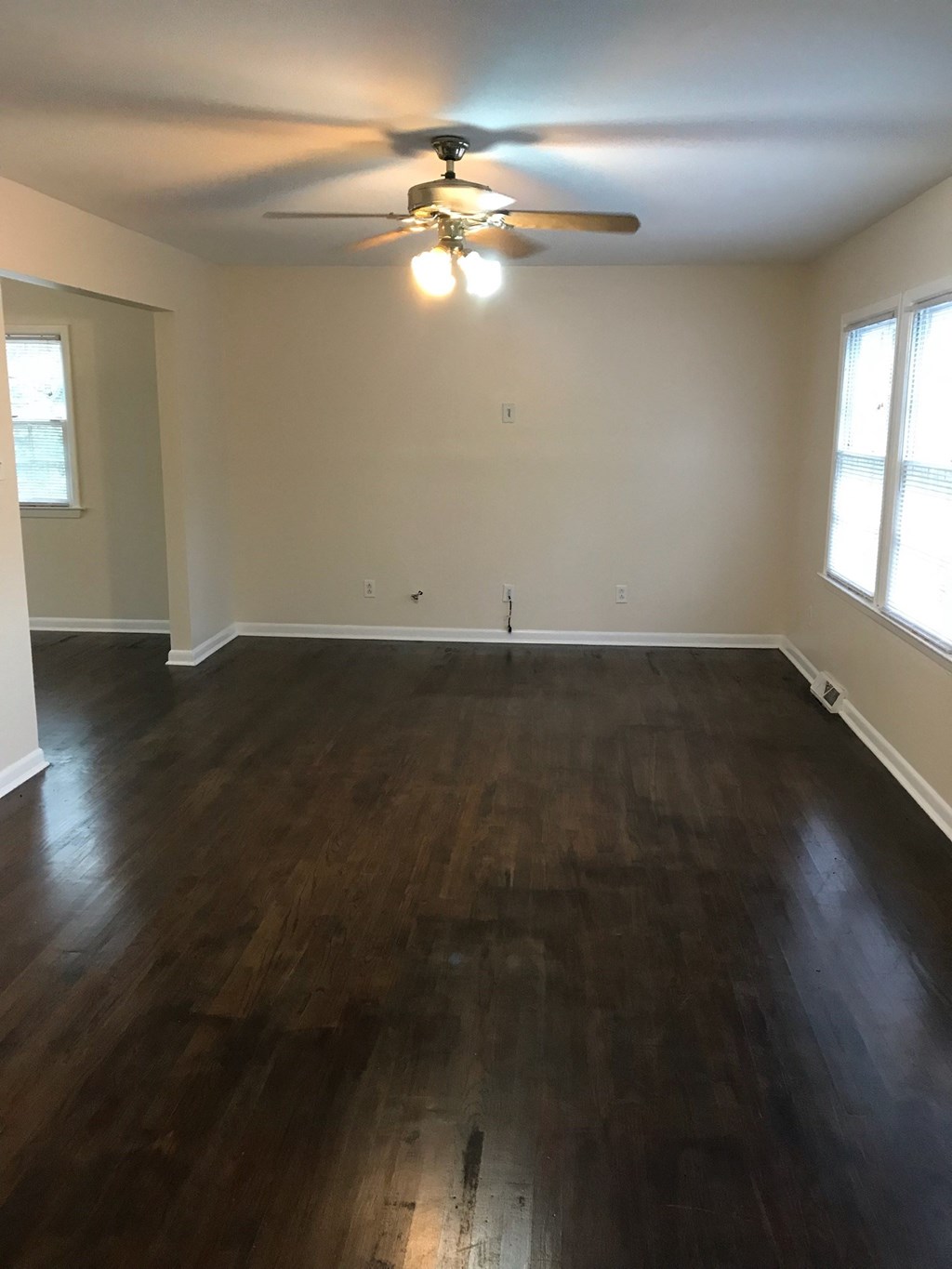 an empty living room with wooden floors and a ceiling fan