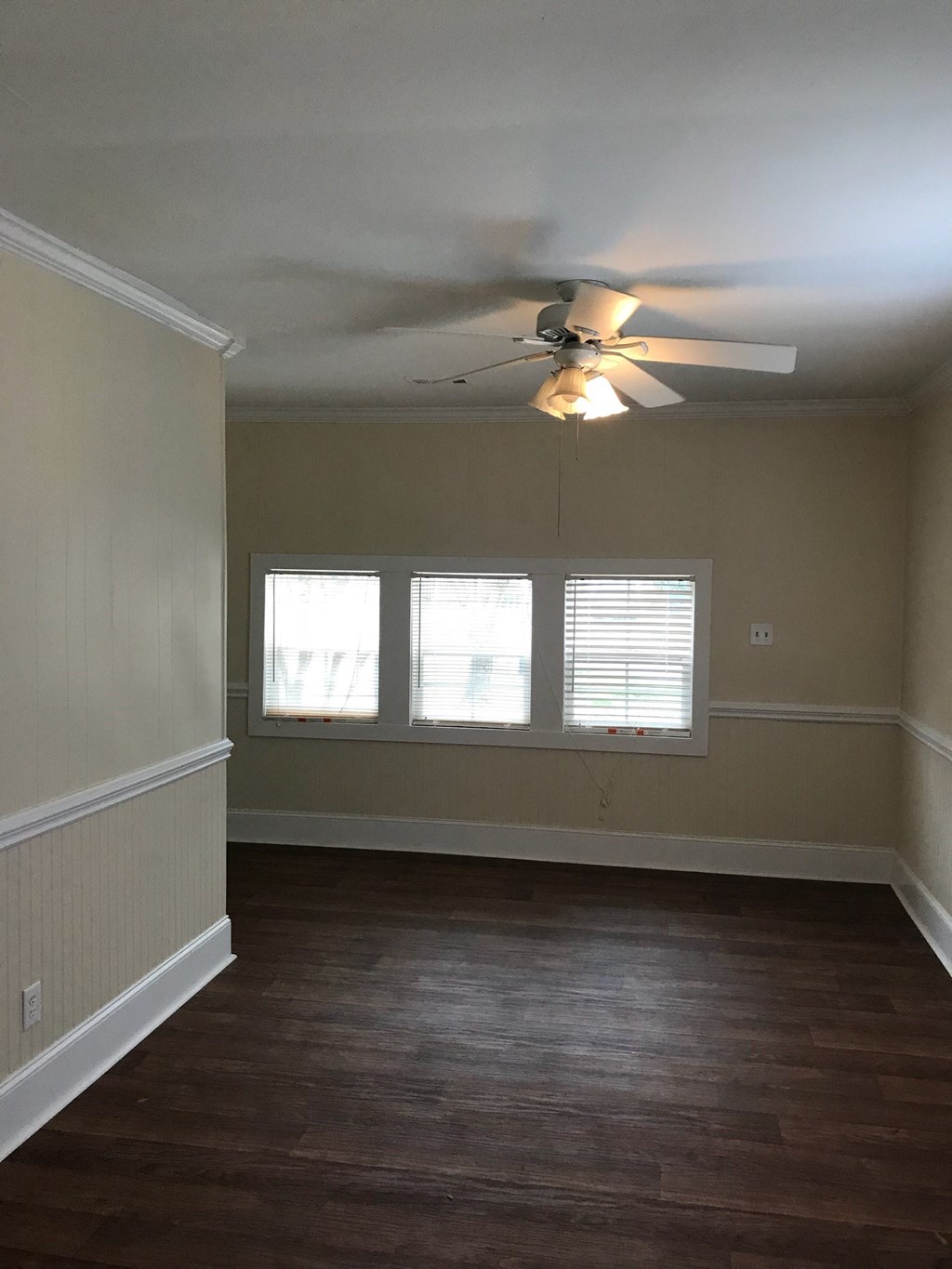 A room with a ceiling fan and wooden flooring.