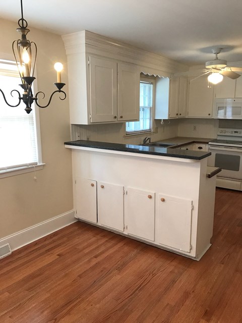 A kitchen with white cabinets and a wooden floor.