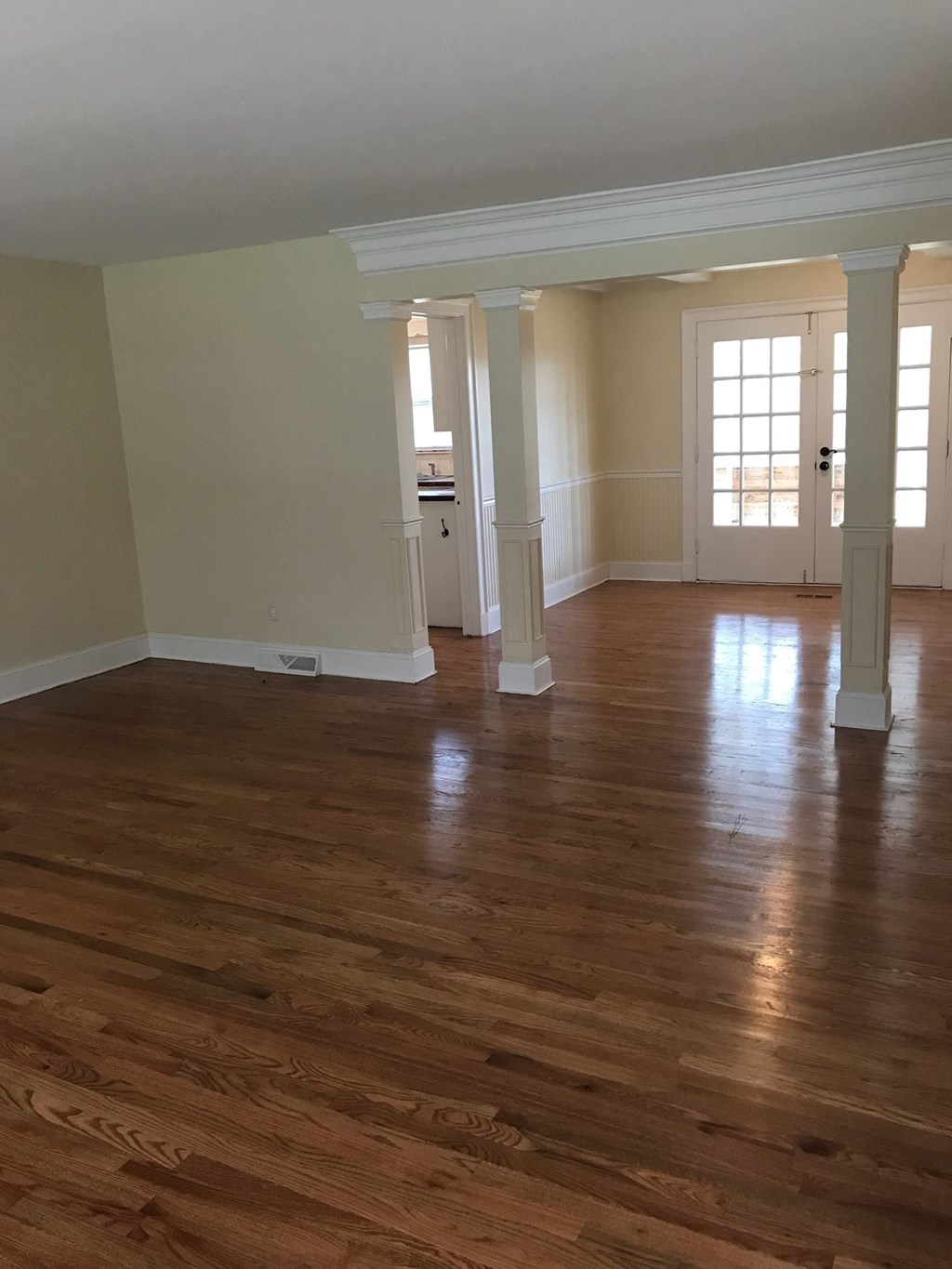A room with wooden floors and white columns.