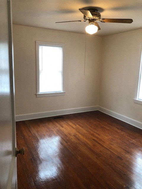 an empty room with a ceiling fan and wood floors