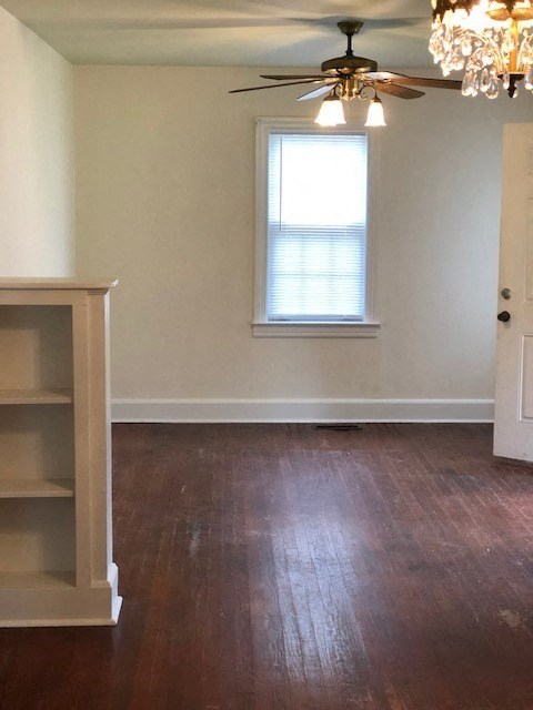 an empty living room with a ceiling fan and a window