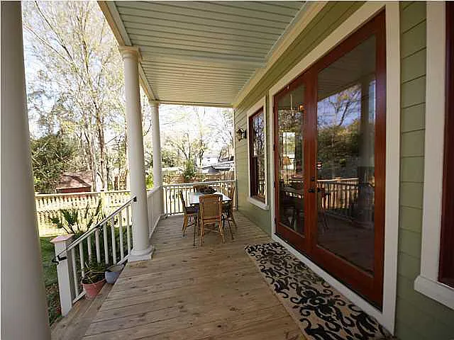 A wooden porch with a table and chairs.