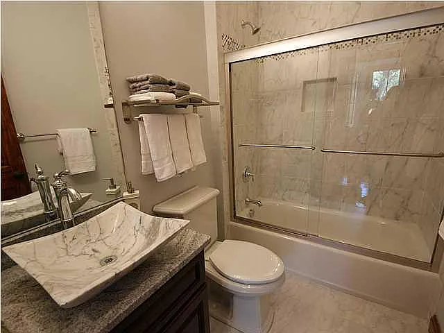 A bathroom with a marble sink and a glass shower stall.