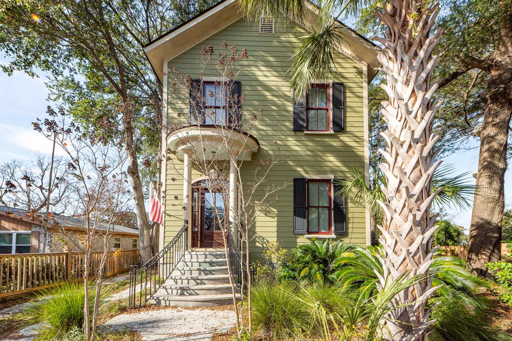 A green house with a flag on the front porch.