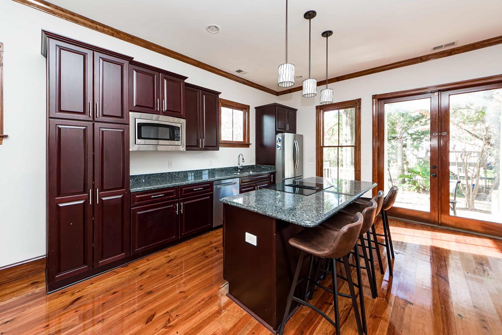 A kitchen with dark wood cabinets and a granite countertop.