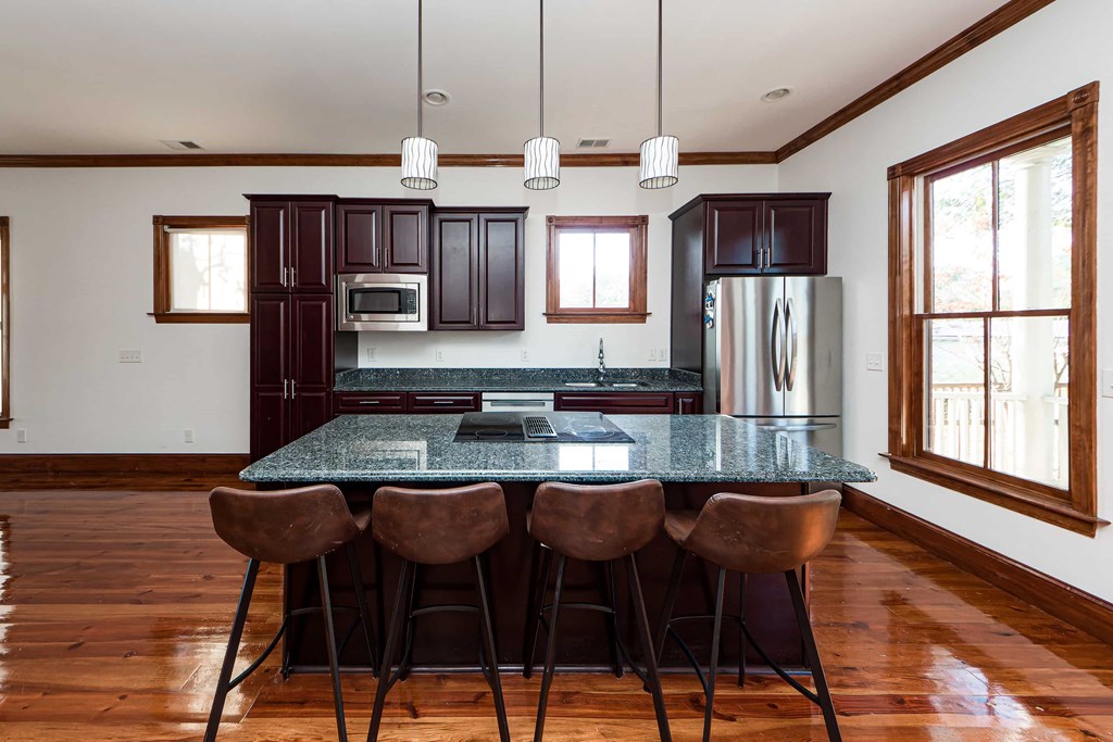 A kitchen with a granite countertop and brown bar stools.