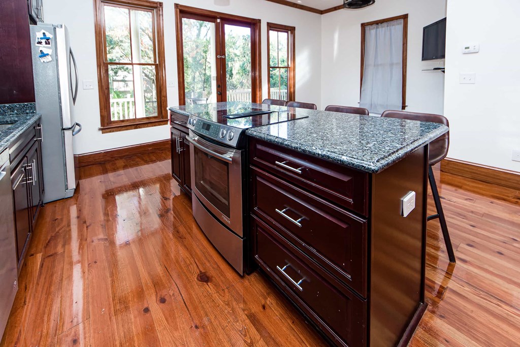 A kitchen with a granite counter top and wooden floors.