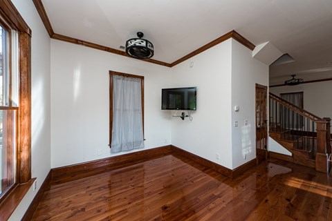 A living room with a wooden floor and a television mounted on the wall.