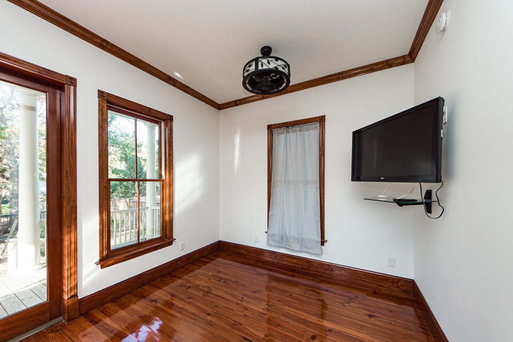 A room with a wooden floor and a flat screen TV mounted on the wall.