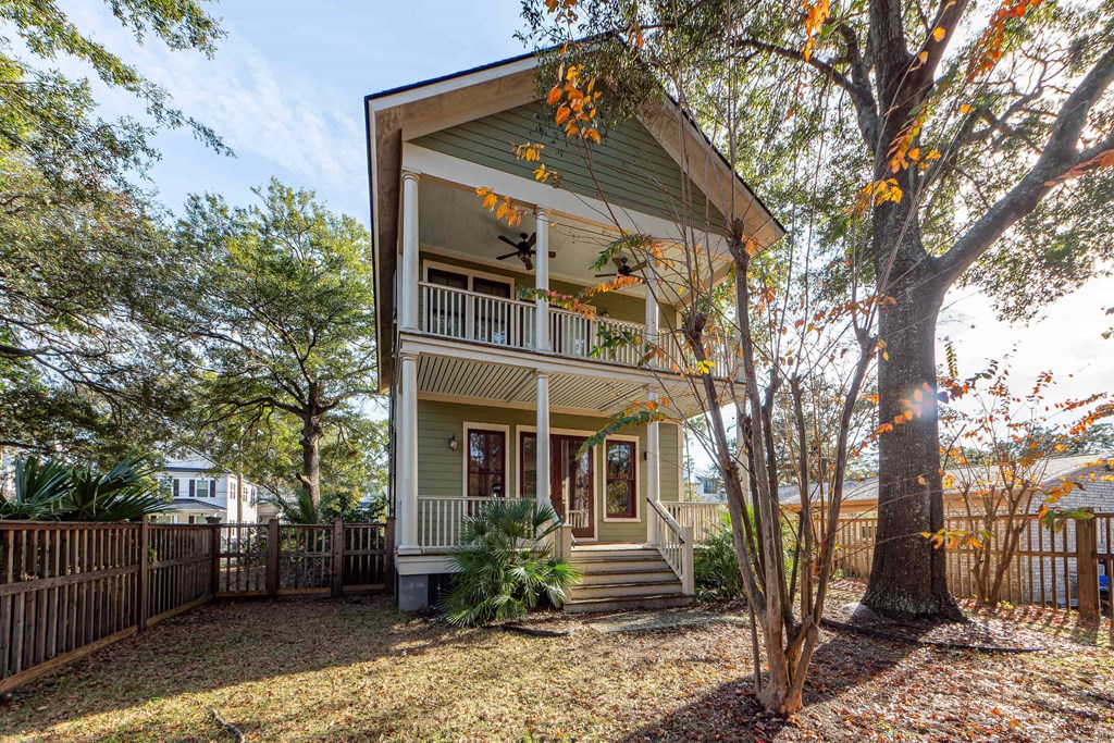 A house with a green front and a tree with orange leaves.
