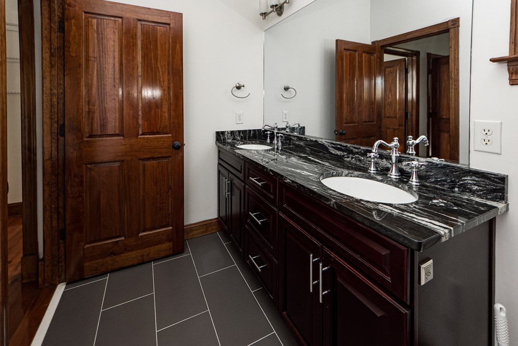 A bathroom with a sink, mirror, and wooden door.
