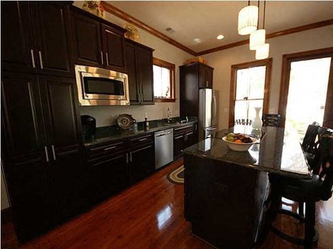 A kitchen with dark wood cabinets and a black island.