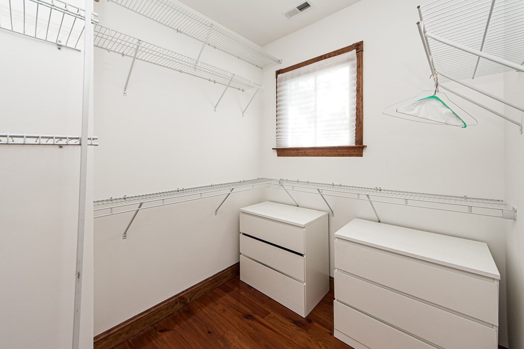 A white closet with a window and a white bench.