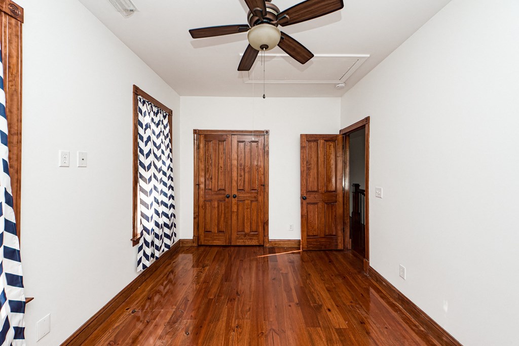 A room with a ceiling fan and wooden floors.