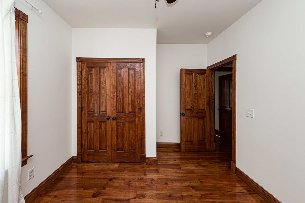 A room with a white wall and a brown wooden door.