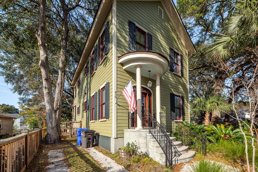 A green house with a flag on the front porch.