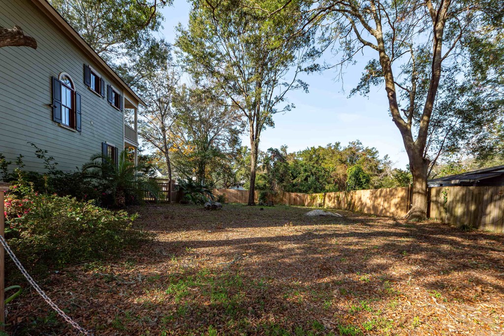 A backyard with a house, trees, and a fence.
