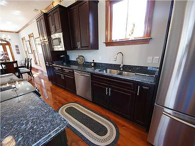 A kitchen with dark wood cabinets and a black granite counter.