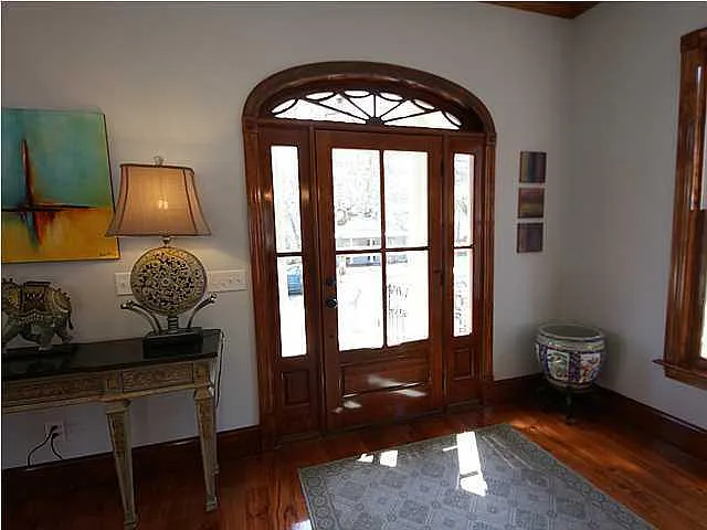 A room with a table, a lamp, a chair and a painting.