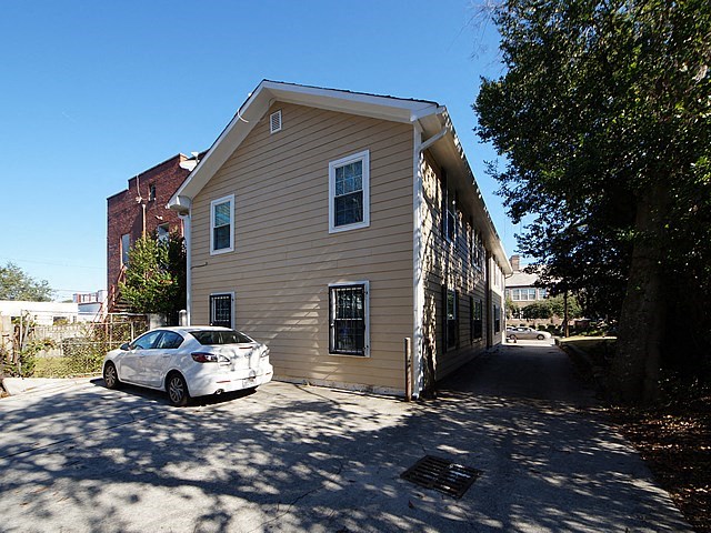 a white car parked in front of a tan house
