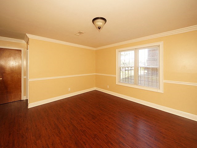 an empty living room with wood floors and a window